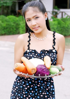 Азиатка позирует с овощами на улице и раздевается