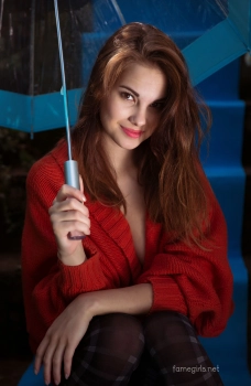Девушка в красной кофте раздевается и позирует голая с зонтиком